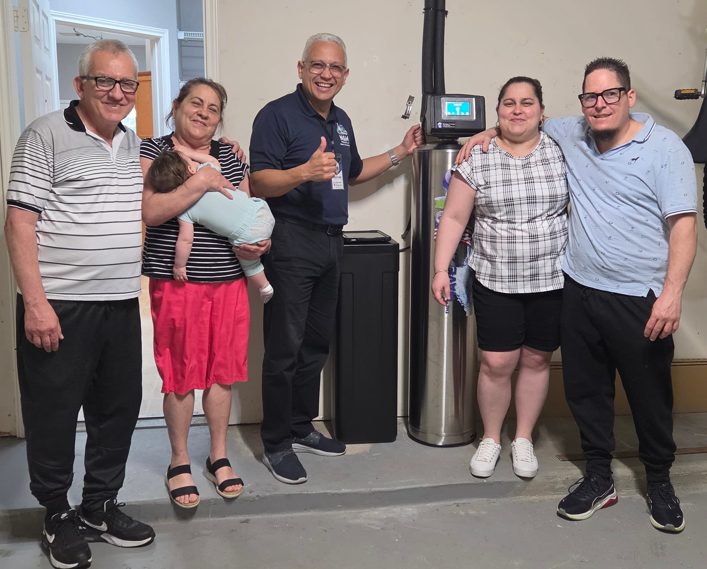 Happy customer next to whole-home water purification system